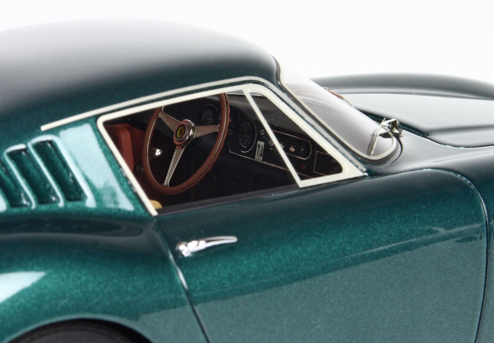 Primo piano di un modellino di auto d'epoca verde con interni dettagliati e volante in legno, disponibile su Vroomi.