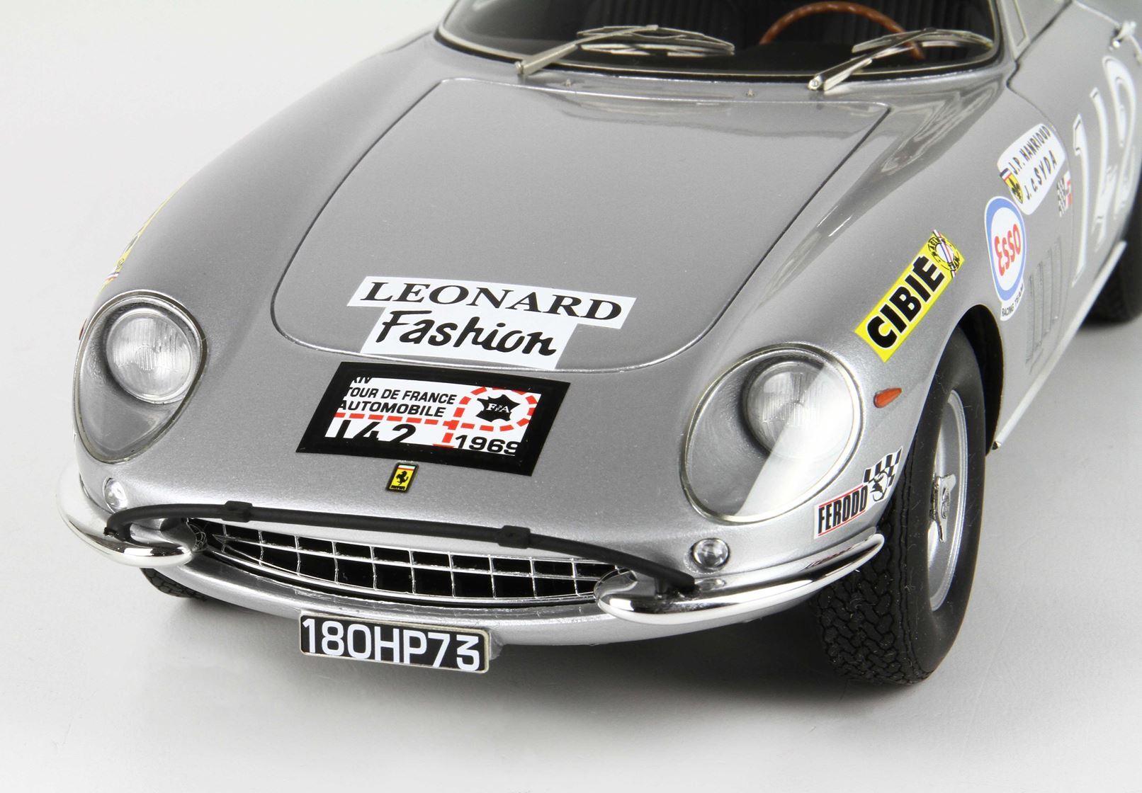 Modellino classico in argento di un'auto da corsa Ferrari con adesivi vintage e targa 180HP73, disponibile su Vroomi.