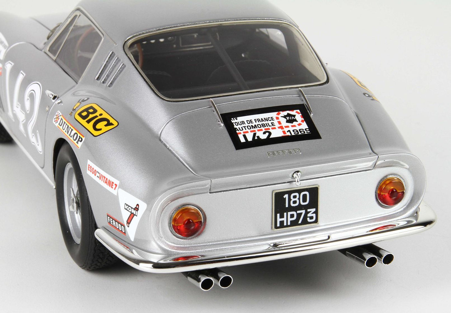 Vista posteriore di un modellino vintage argentato di una Ferrari da corsa con adesivi, disponibile su Vroomi.