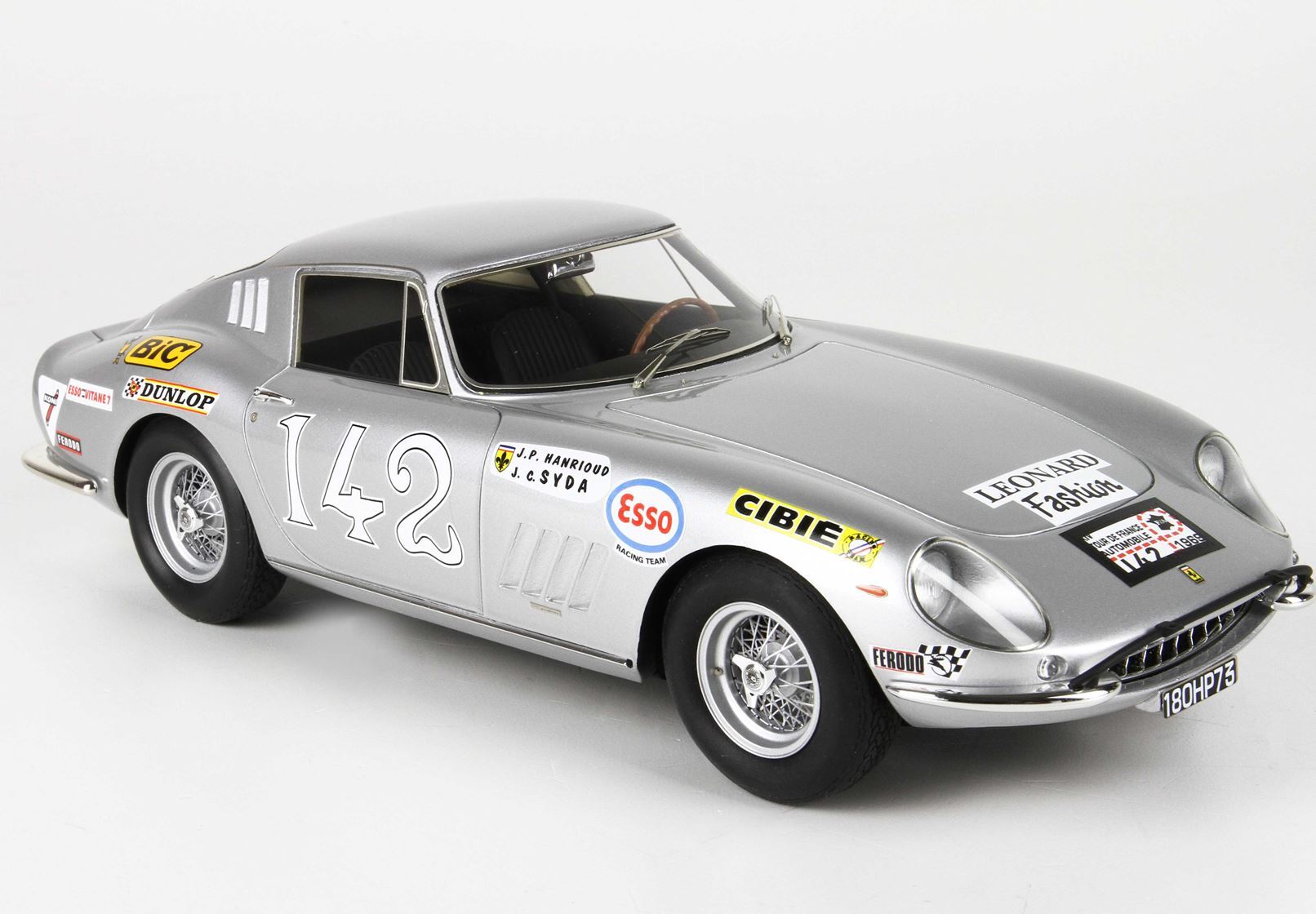 Modello di auto da corsa classica color argento numero 142 con i loghi degli sponsor, i raggi delle ruote e gli interni dettagliati, disponibile su Vroomi.