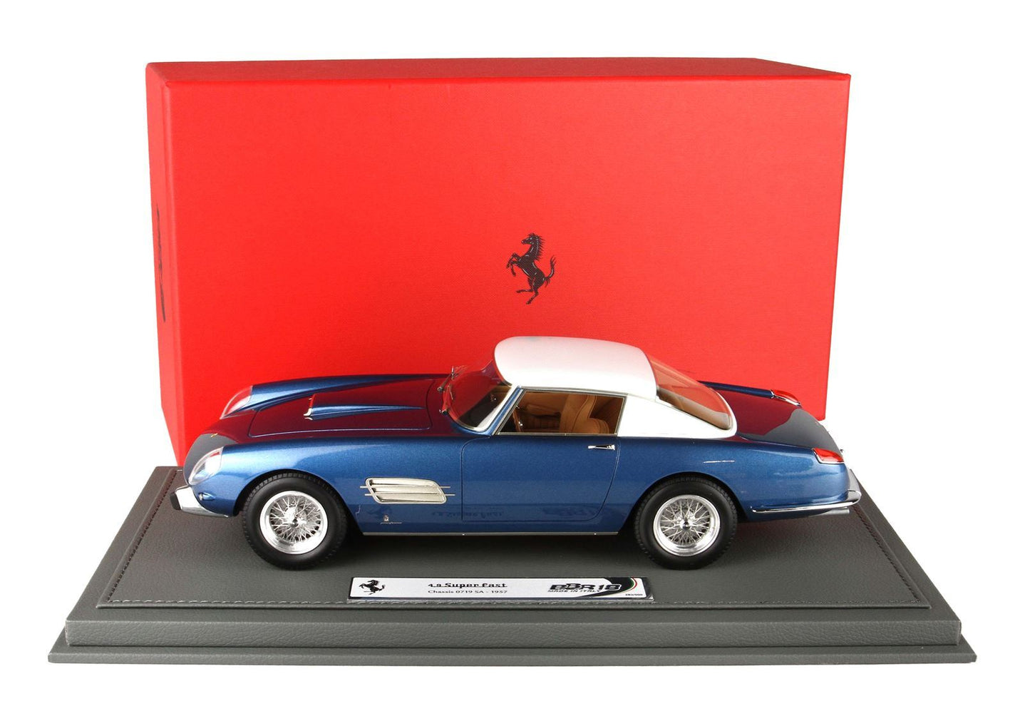Modellino di Ferrari blu e bianco in scala 1:18 su base espositiva con scatola Ferrari rossa, disponibile tramite Vroomi.