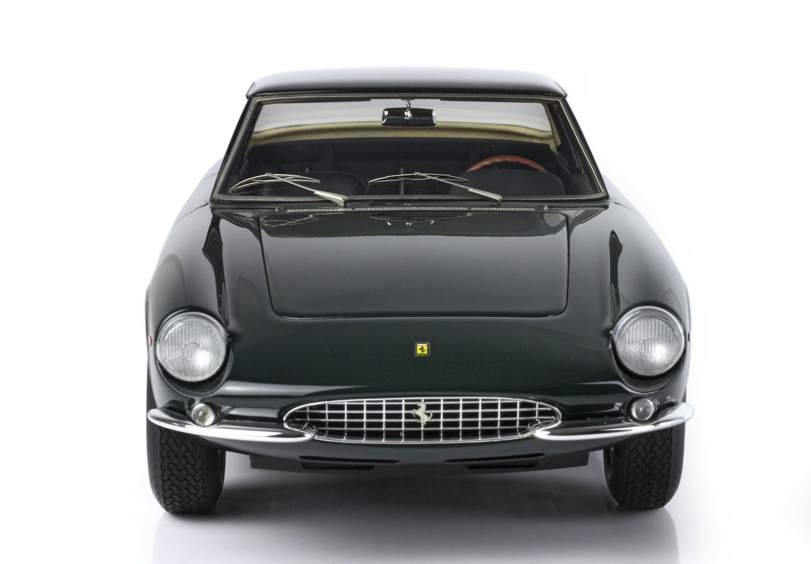 Vista frontale di una classica Ferrari GT verde scuro con griglia cromata, disponibile sulla piattaforma Vroomi.