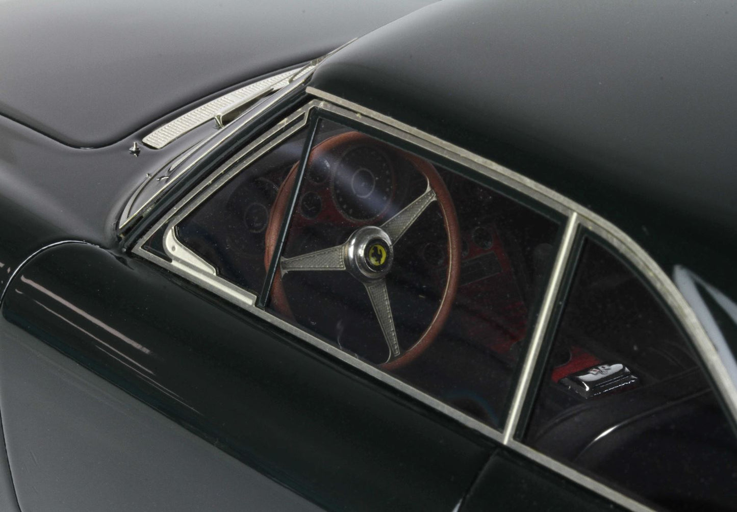 Primo piano degli interni di un'auto d'epoca con volante e cruscotto Ferrari, disponibile su Vroomi.