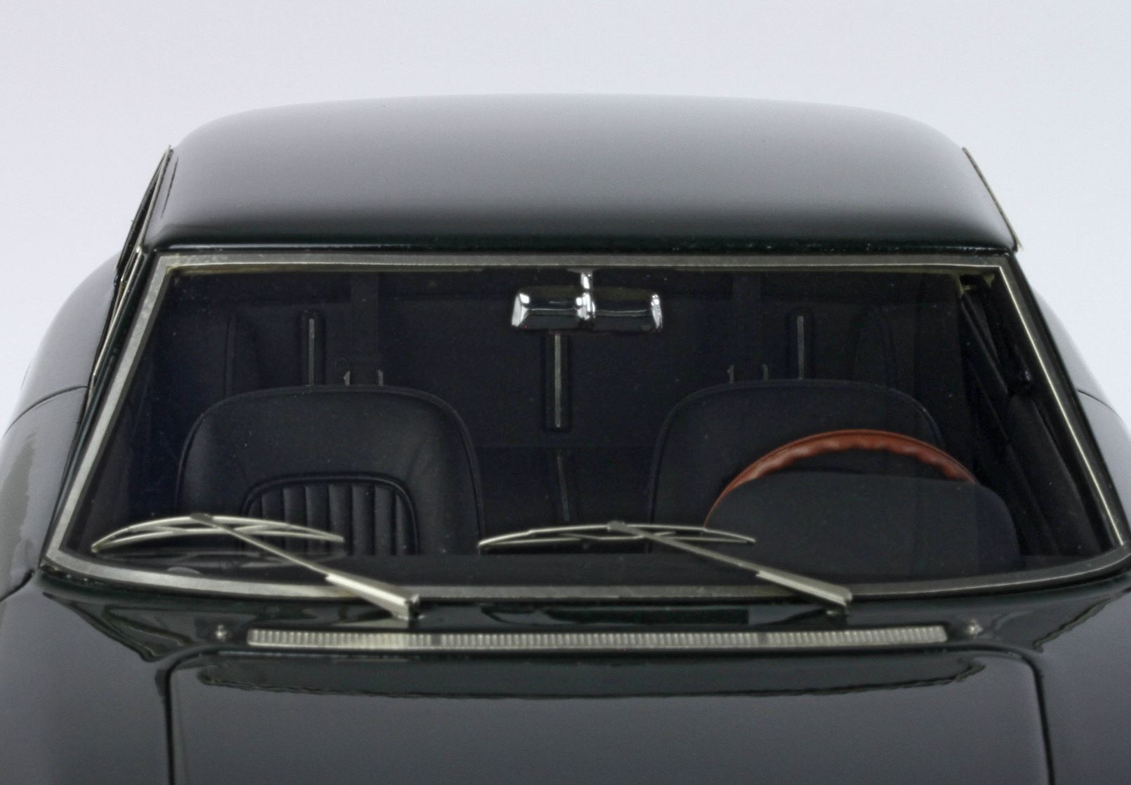 Primo piano del parabrezza anteriore di un'auto d'epoca nera con doppio tergicristallo e volante marrone, che puoi comprare tramite Vroomi.