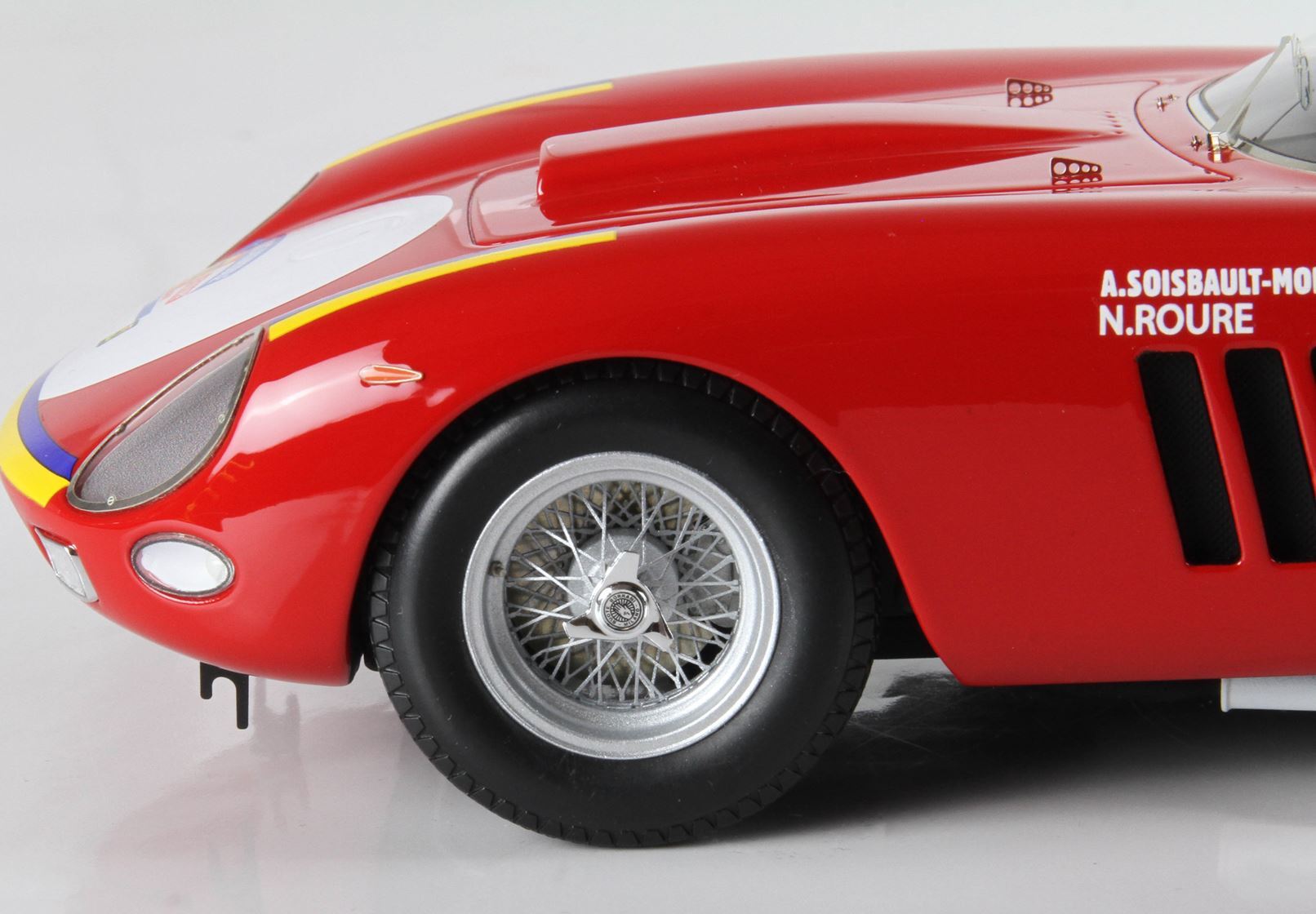 Close-up of red vintage race car front wheel and hood with driver names, available on Vroomi platform
