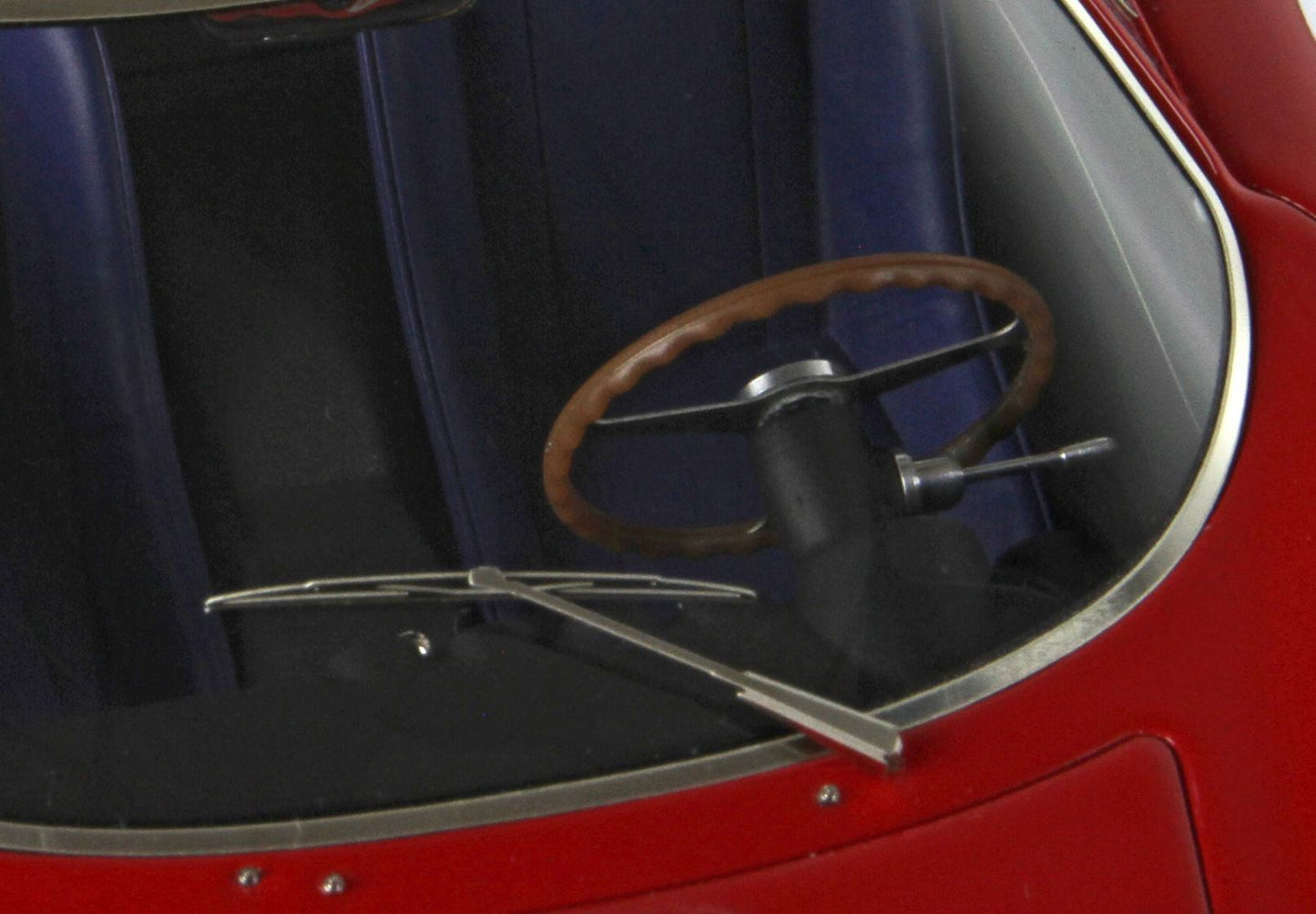 Close-up of vintage car interior with wooden steering wheel and blue seats, red exterior, available on Vroomi