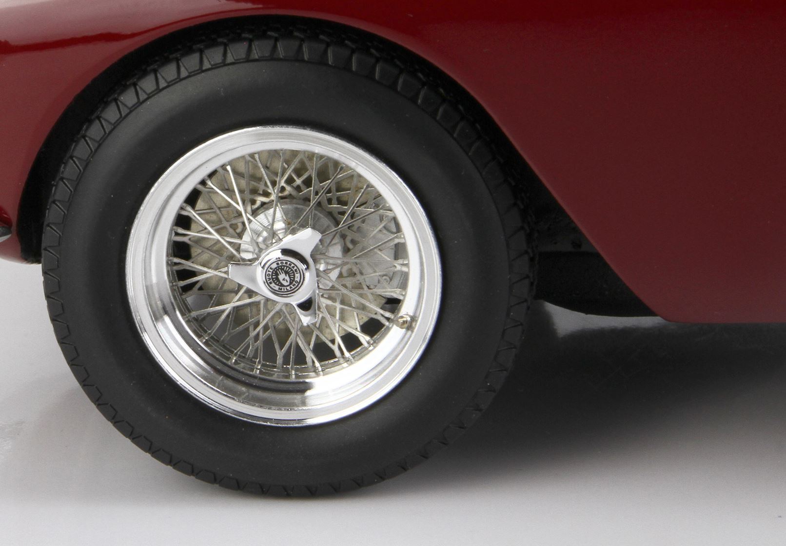 Primo piano della ruota a raggi metallici di un'auto d'epoca con coprimozzo knock-off su carrozzeria marrone rossiccio, disponibile su Vroomi.