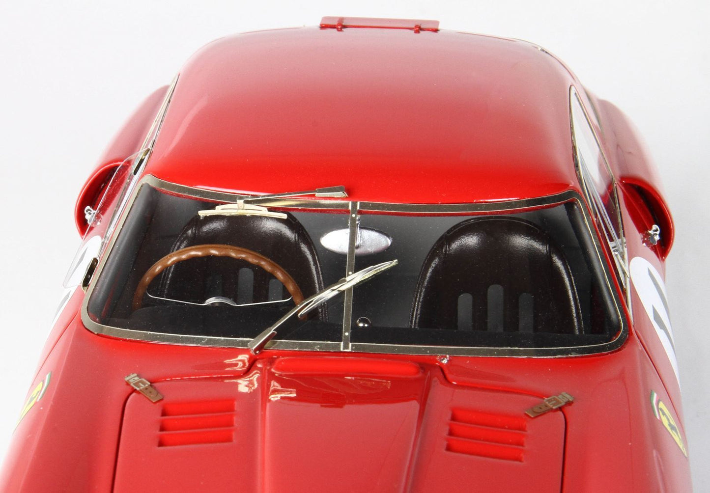 Close-up of a red vintage race car model with detailed windshield, brown steering wheel, and black seats, now featured on Vroomi