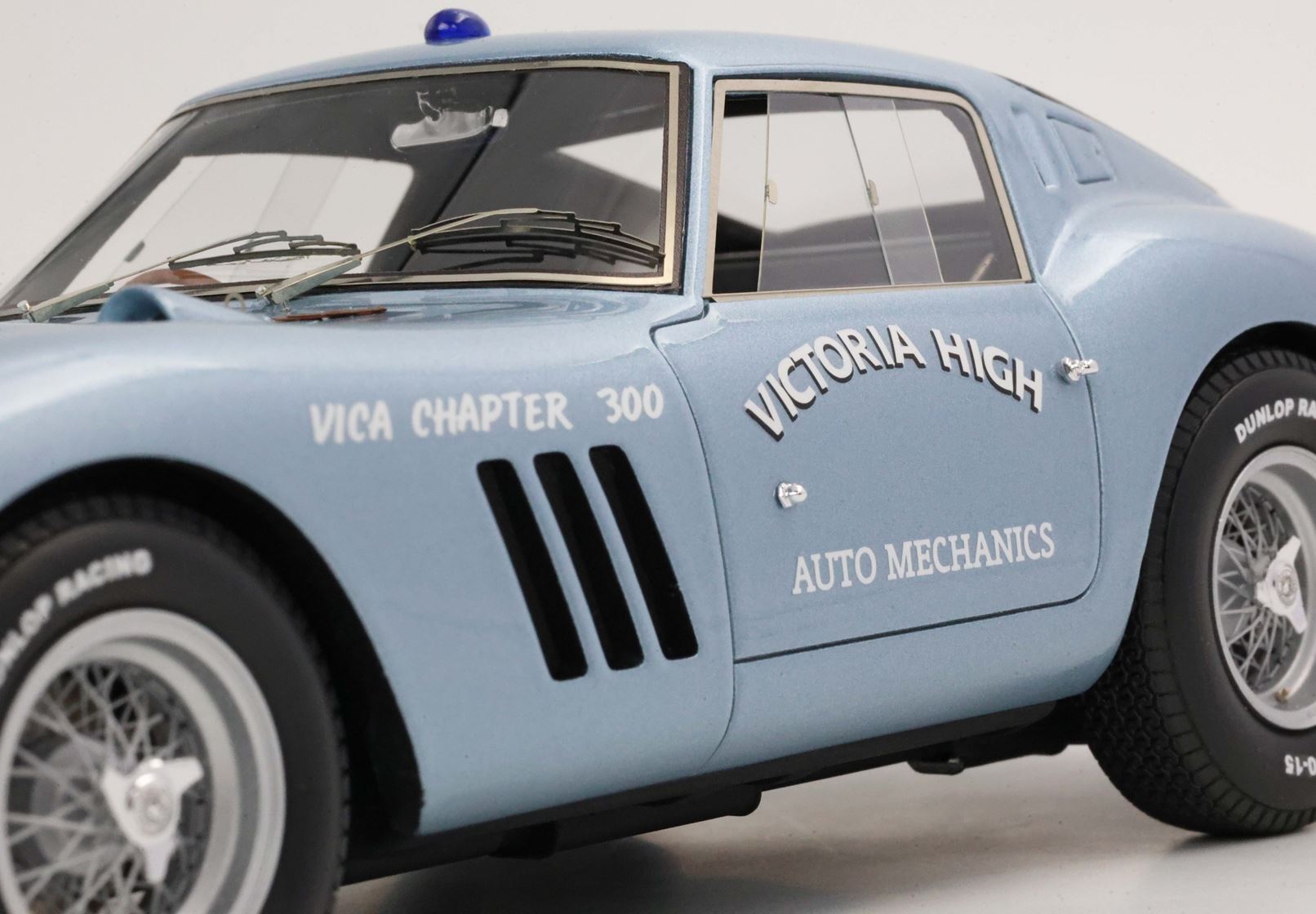 Primo piano di un modellino di auto da corsa vintage azzurro con il marchio Victoria High Auto Mechanics, in vendita su Vroomi.