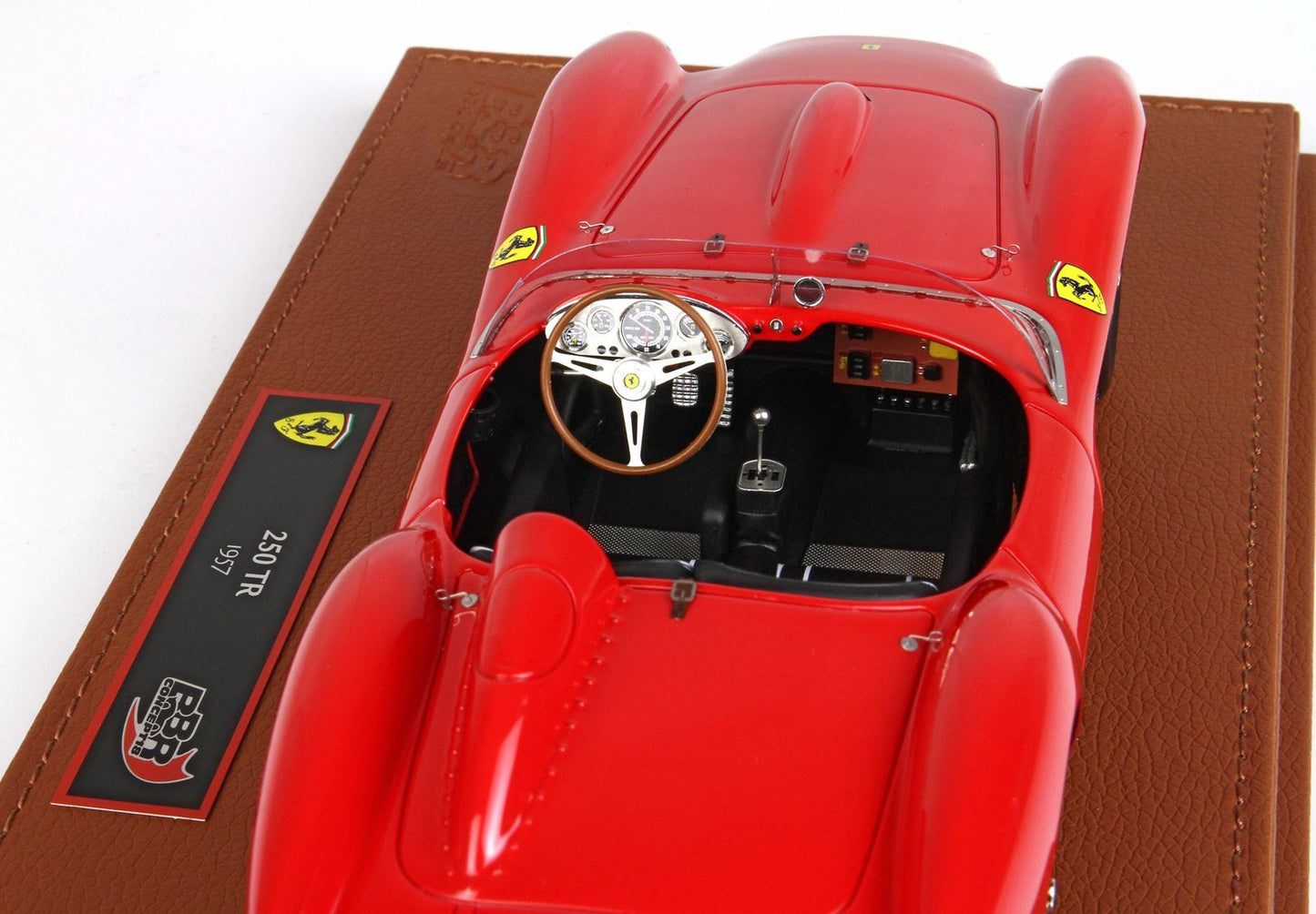 Modellino dettagliato di una Ferrari 250 TR del 1957 con volante in legno, esposto su una base marrone, in vendita su Vroomi.