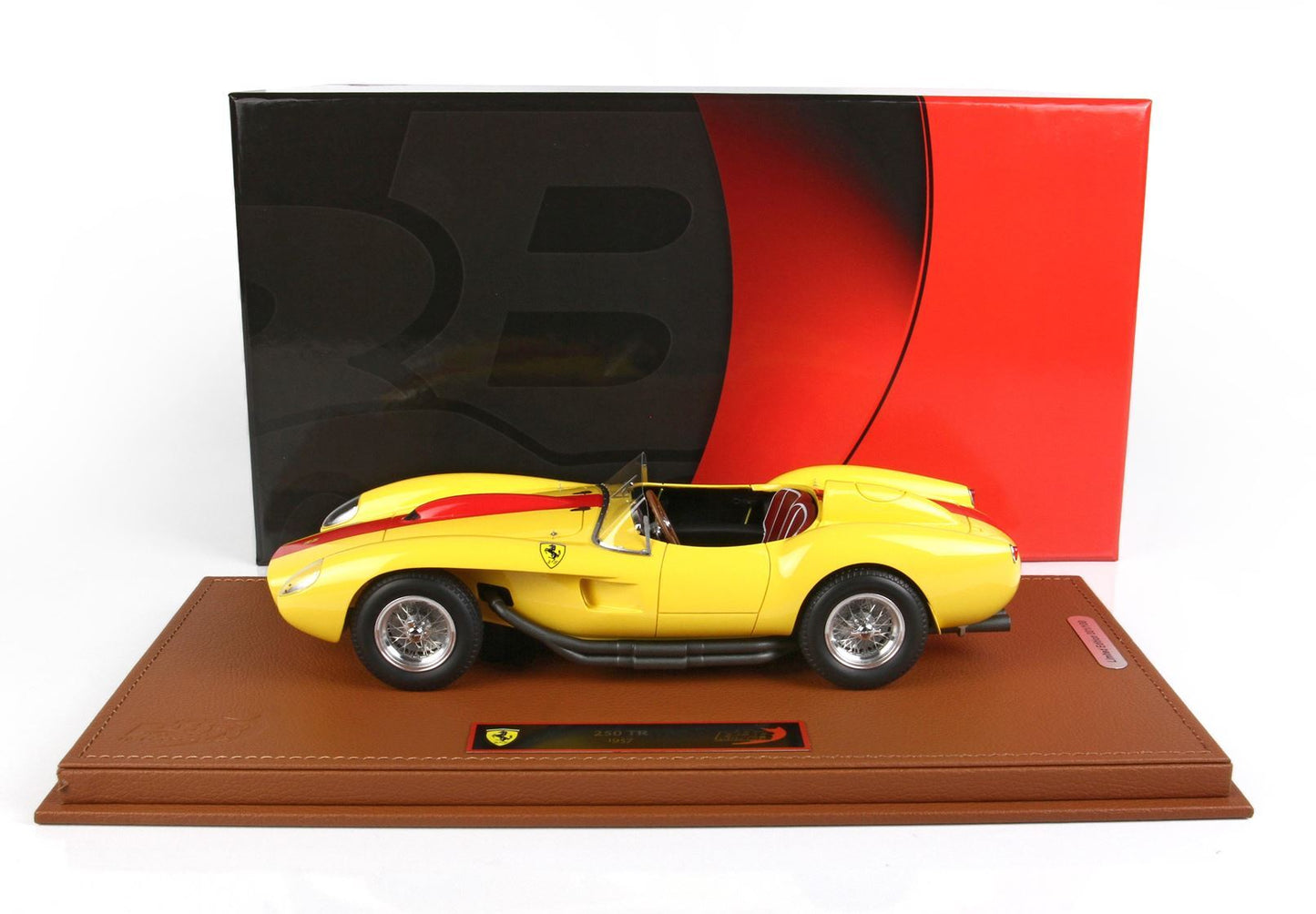 Modellino di Ferrari 250 TR del 1957 giallo su base marrone con sfondo nero e rosso, che puoi comprare tramite Vroomi.