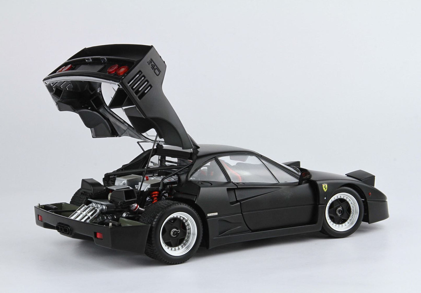 Matte black Ferrari F40 model car with open rear engine bay showcasing detailed components, available on Vroomi