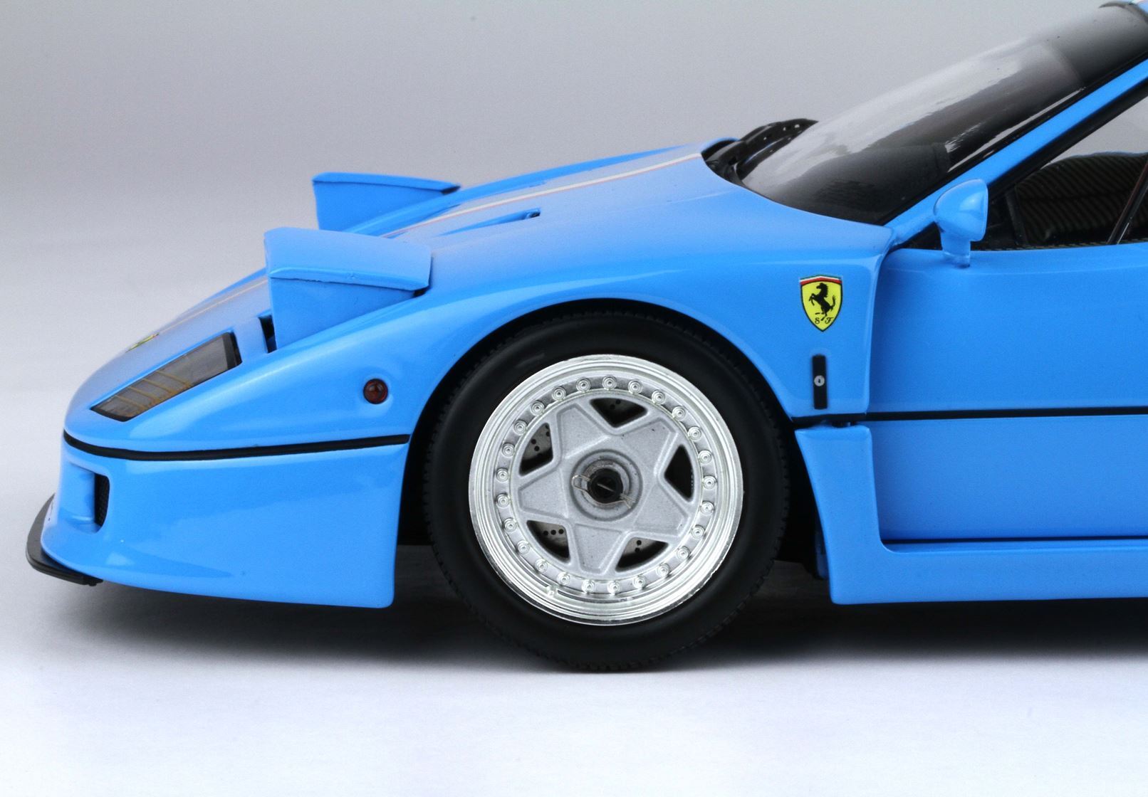 Close-up of blue Ferrari sports car front wheel with iconic logo, available now on Vroomi