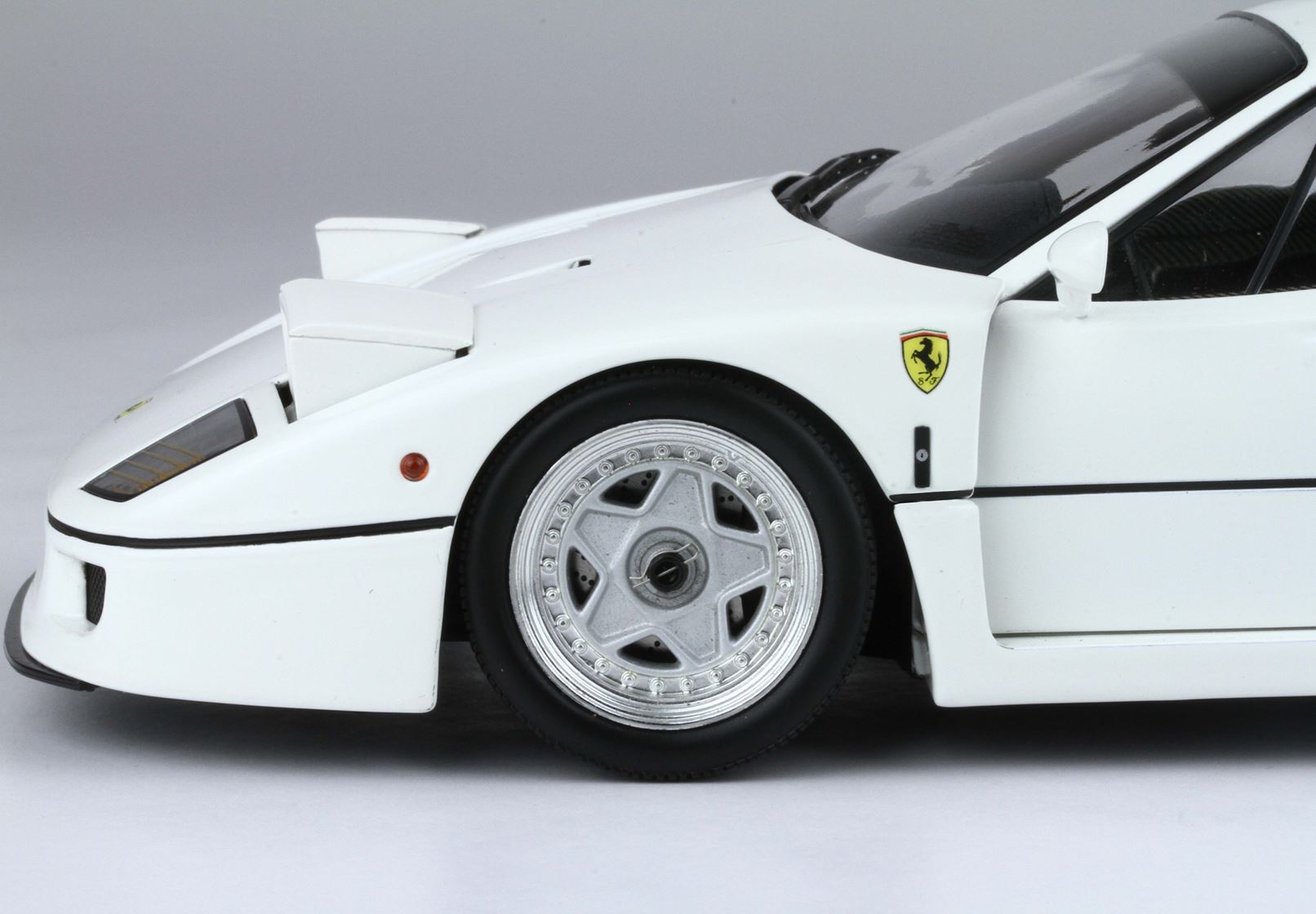 Close-up of white Ferrari F40 front wheel and badge, detailed model car available on Vroomi