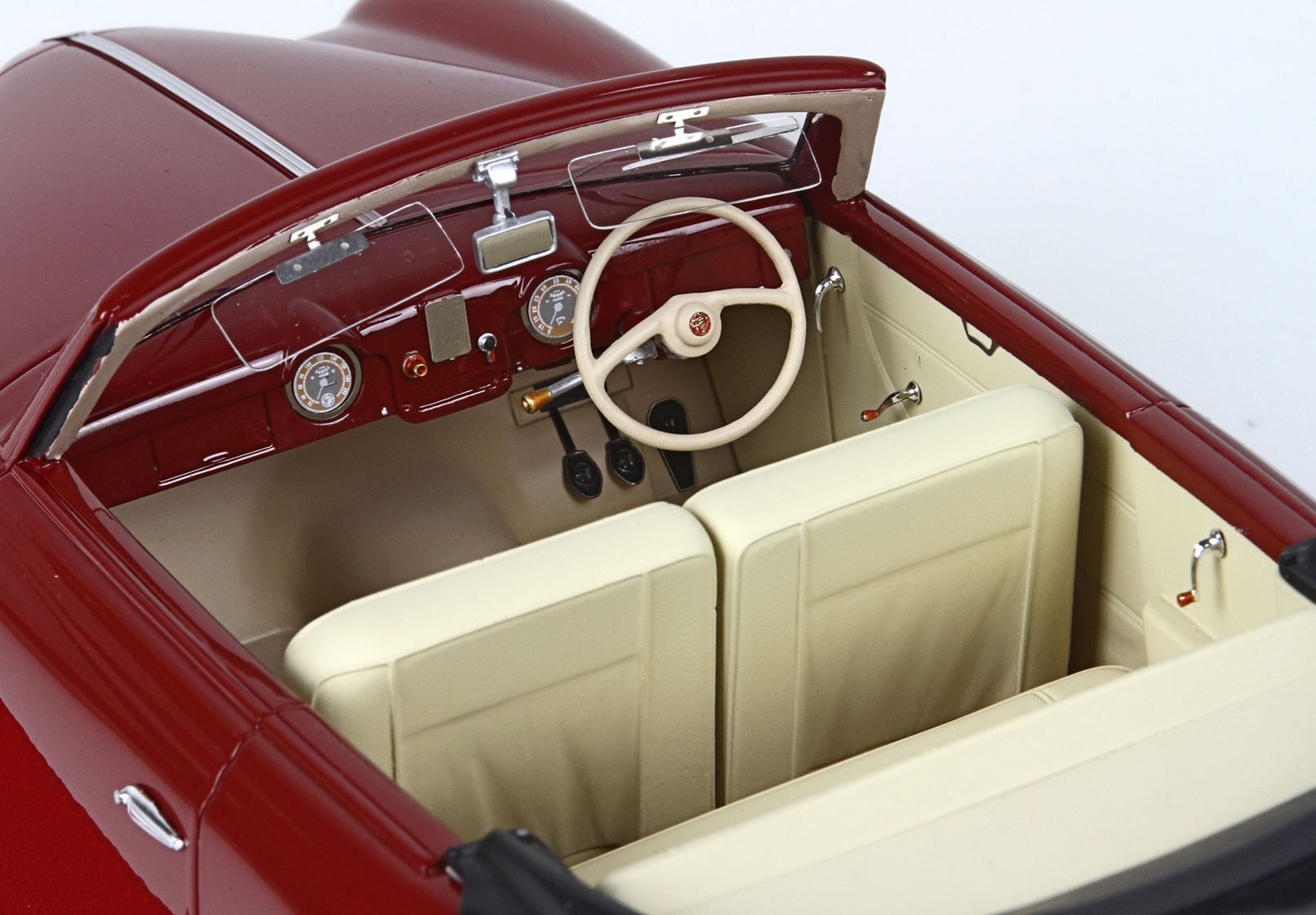 Primo piano dell'interno di un'auto d'epoca decappottabile con sedili color crema e cruscotto rosso, disponibile su Vroomi.