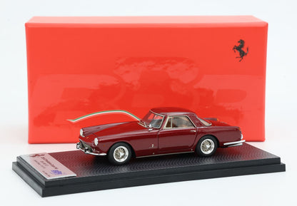 Modellino di Ferrari 250 GT marrone su base nera con sfondo rosso della scatola Ferrari, disponibile su Vroomi.